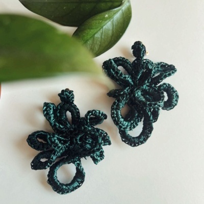 Brincos florais em fio trançado verde escuro sobre fundo branco com folhas verdes