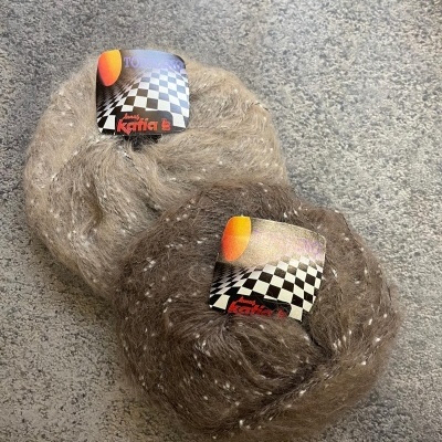 Dois novelos de lã castanha com pompons e rótulos xadrez