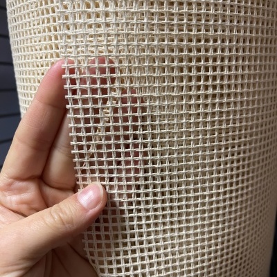 Tecido de algodão cru com padrão de malha quadrada aberta com mão a segurá-lo.