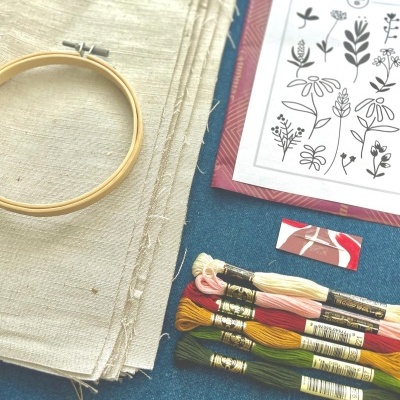 Materiais para bordado com tecido, bastidor, linhas coloridas e padrão de flores preto e branco