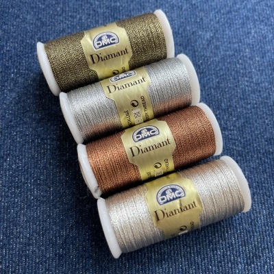 Carretéis de linha metálica DMC Diamant em várias cores sobre tecido azul