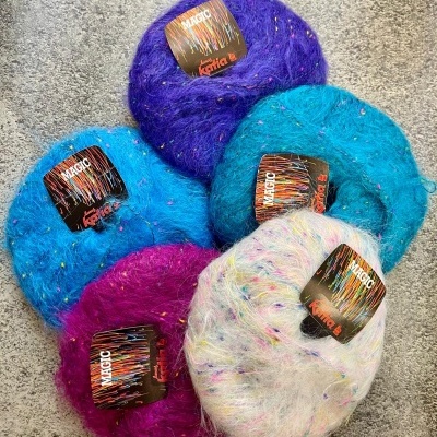 Cinco novelos de lã felpuda colorida com etiquetas e superfície cinzenta.