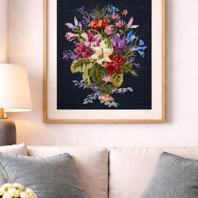 Quadro decorativo com bordado de flores coloridas em moldura de madeira sobre sofá e almofadas