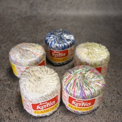 Novelos de fio Katia Flamenco coloridos em superfície cinzenta