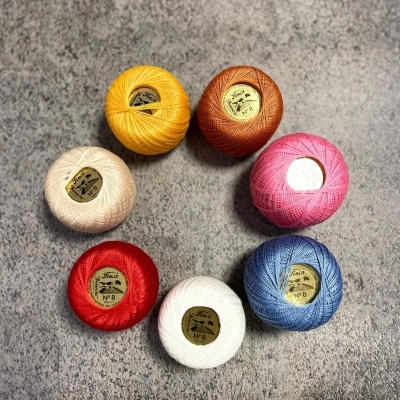 Sete novelos de linha colorida com rótulos Finca Nº 8 sobre fundo cinza