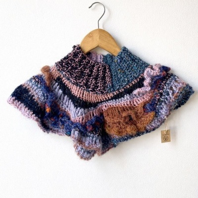 Capa tricô colorida pendurada num cabide de madeira