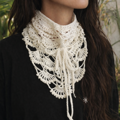 Cachecol triangular em crochê branco com padrão rendado e franjas