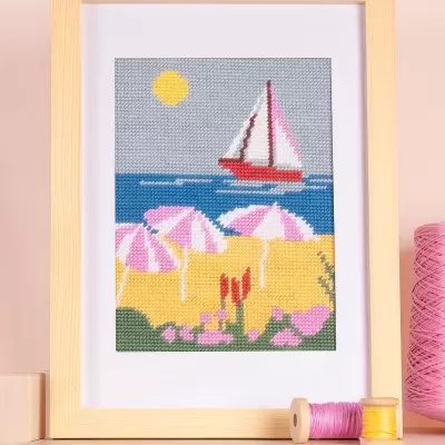 Quadro de bordado com paisagem de praia e barco