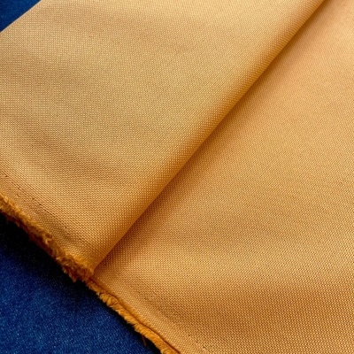 Tecido amarelo mostarda com textura densa sobre superfície azul escura