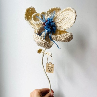 Flor artesanal de crochet creme com centro azul e etiqueta handmade