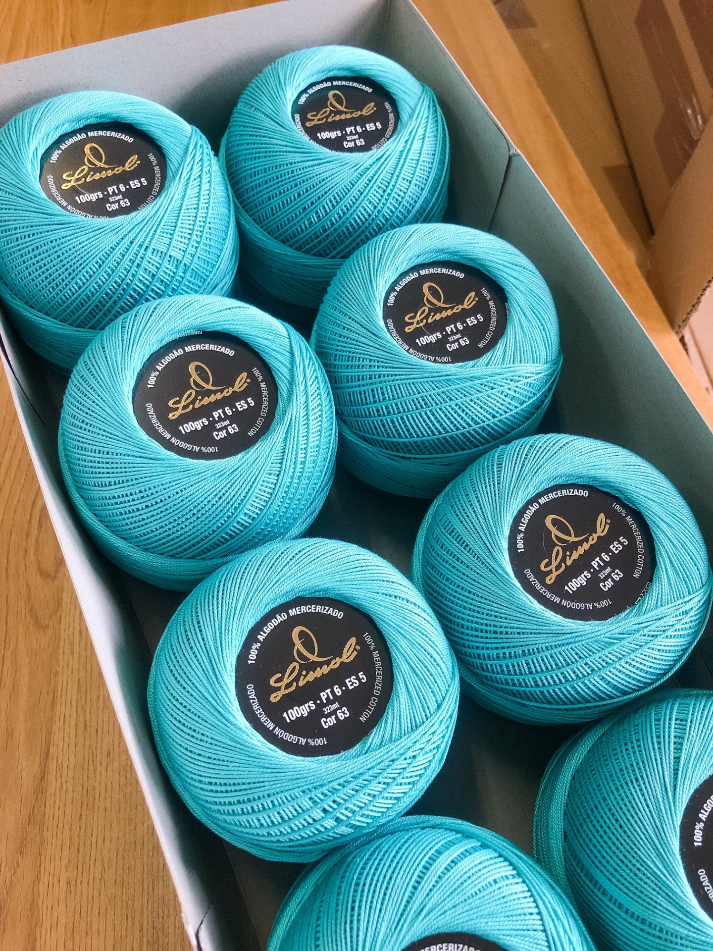 Esferas de linha azul-turquesa com etiquetas negras em caixa branca