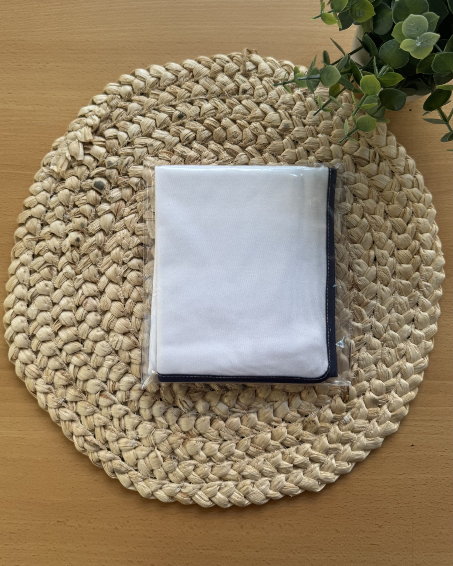 Carteira ou porta-cartões branco e preto em saco plástico sobre tapete redondo bege e mesa de madeira