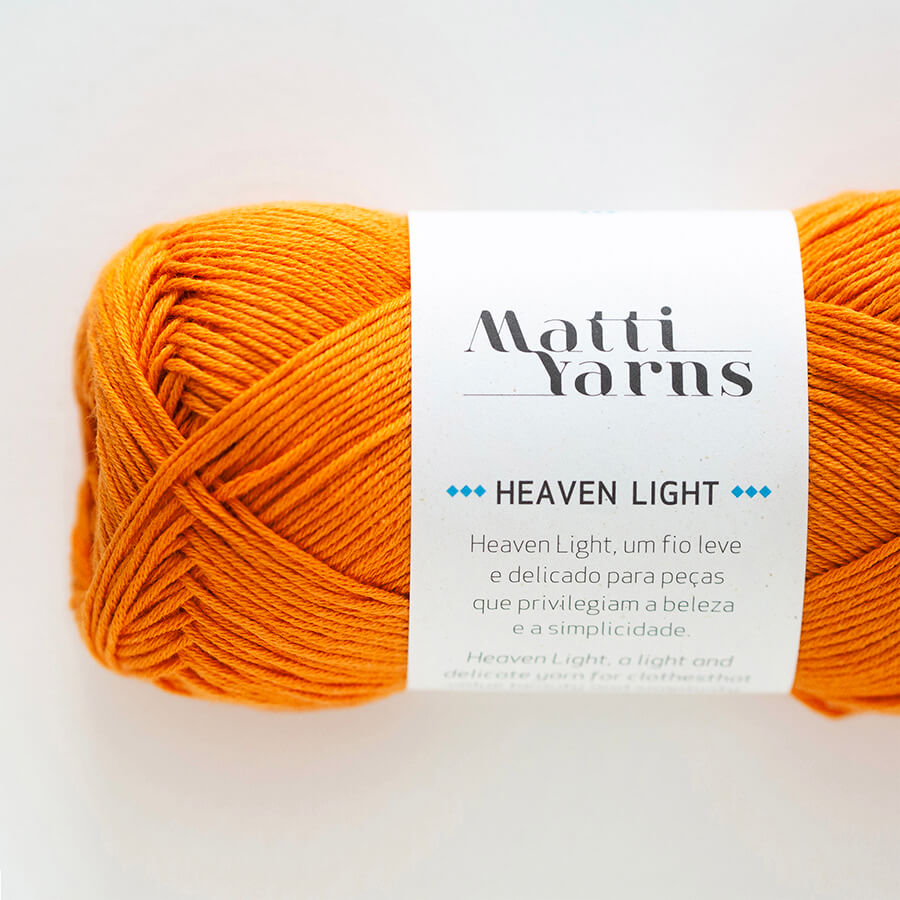 Novelo de fio laranja com etiqueta branca Matti Yarns Heaven Light