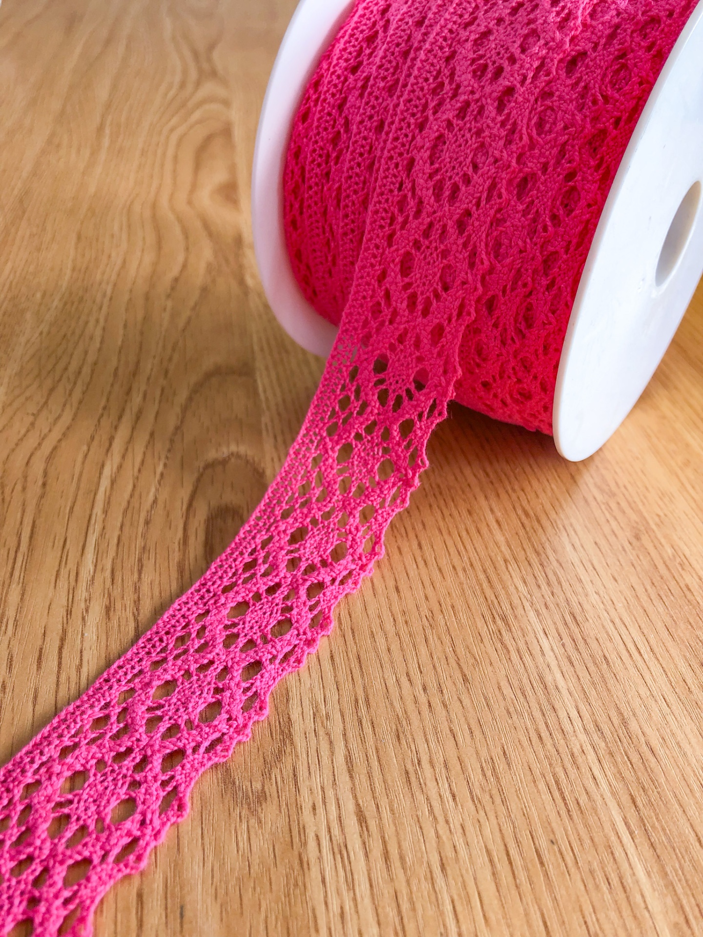 Rolo de fita de renda rosa sobre madeira