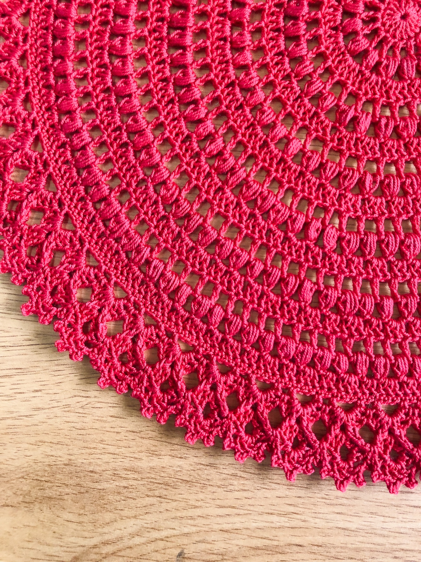 Tapete vermelho em crochet sobre madeira clara