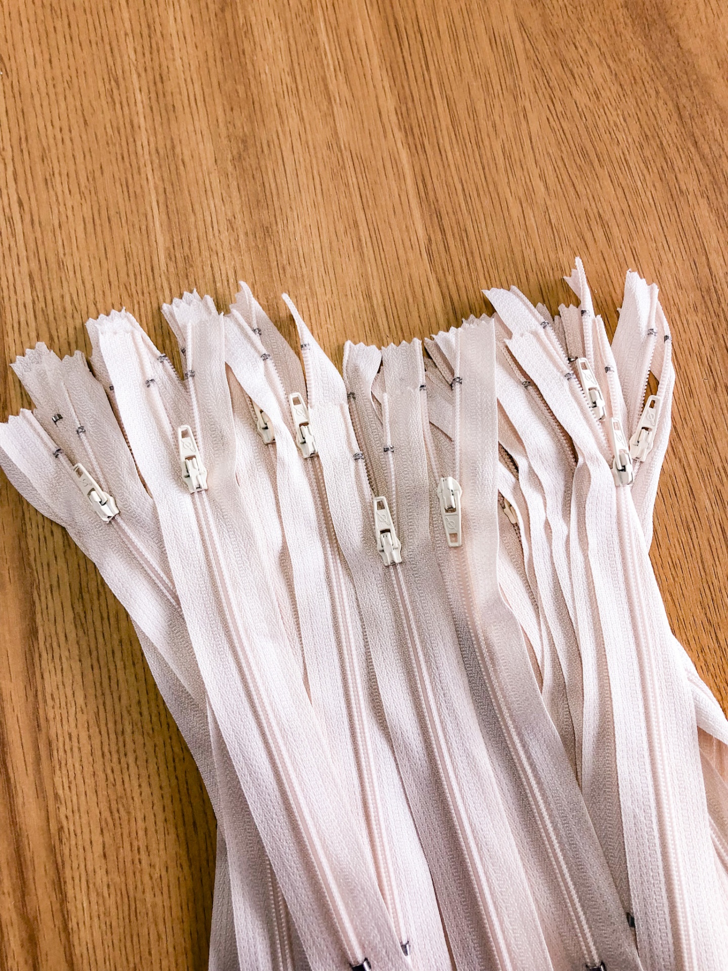 Muitos fechos éclair brancos lado a lado sobre uma superfície de madeira.