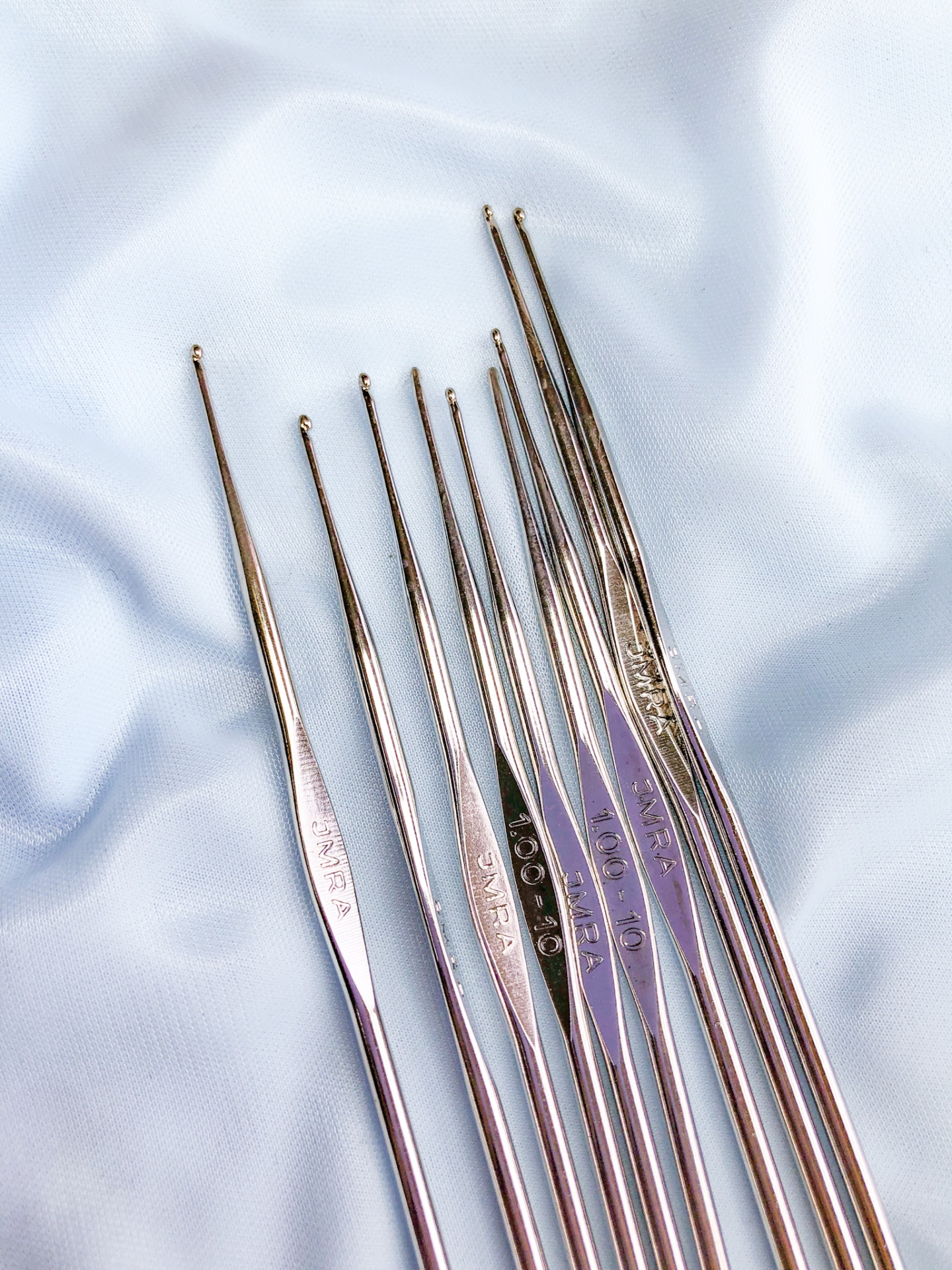 Conjunto de agulhas de croché metálicas prateadas em tecido azul claro