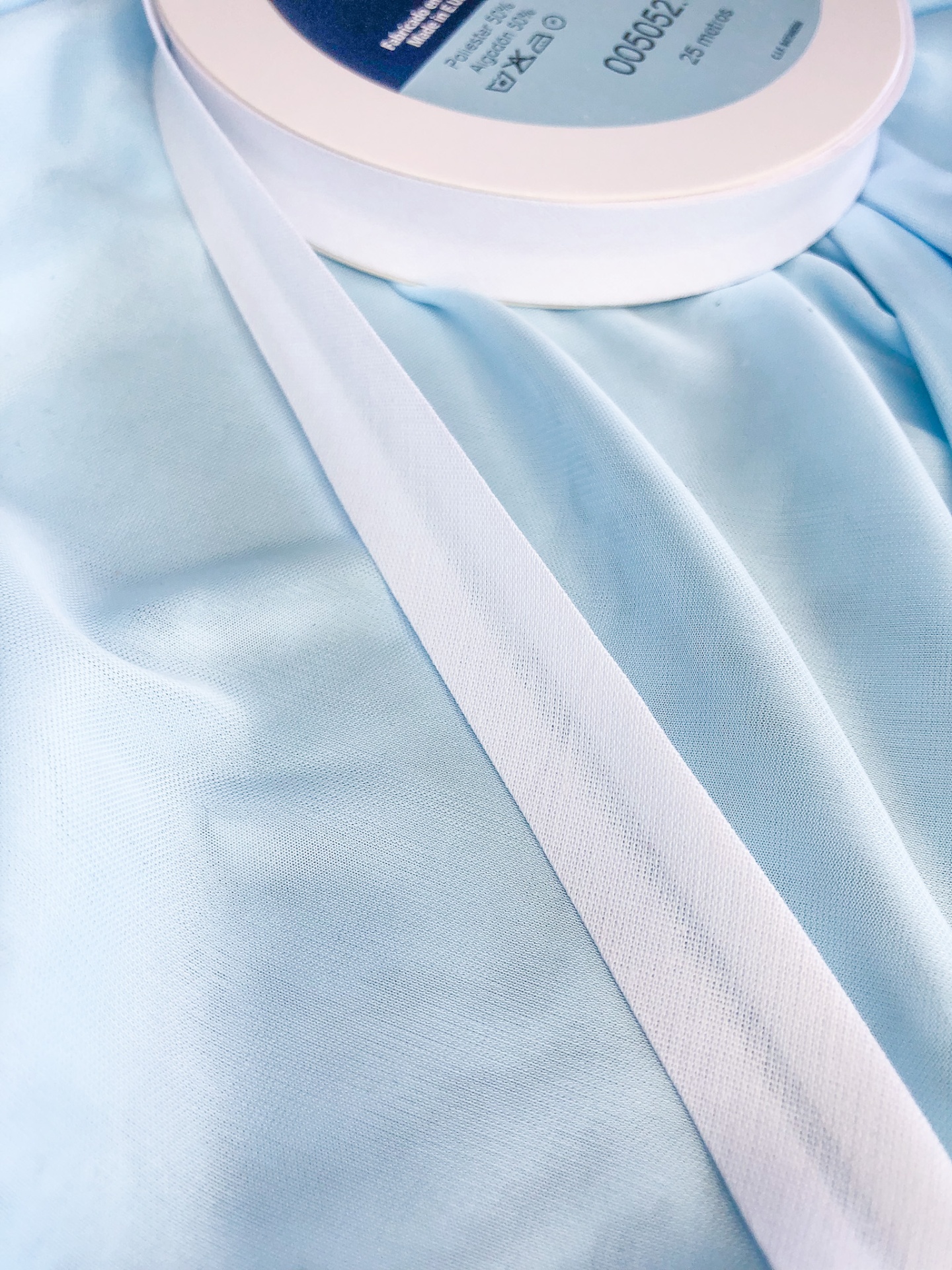 Fita branca numa bobina sobre tecido azul claro