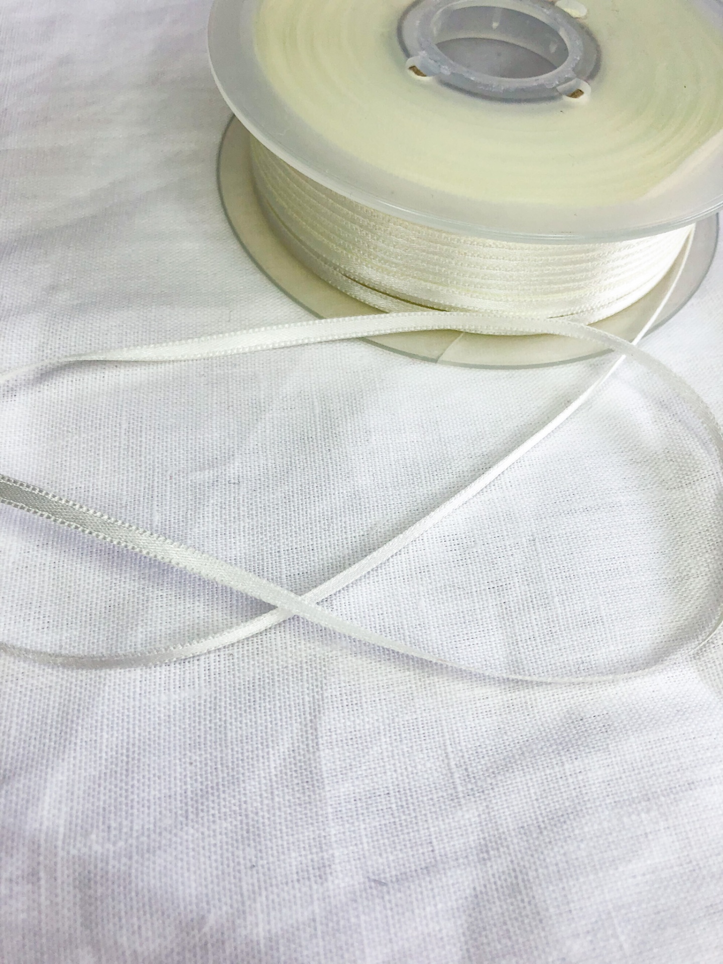 Rolo de fita fina branca sobre tecido branco