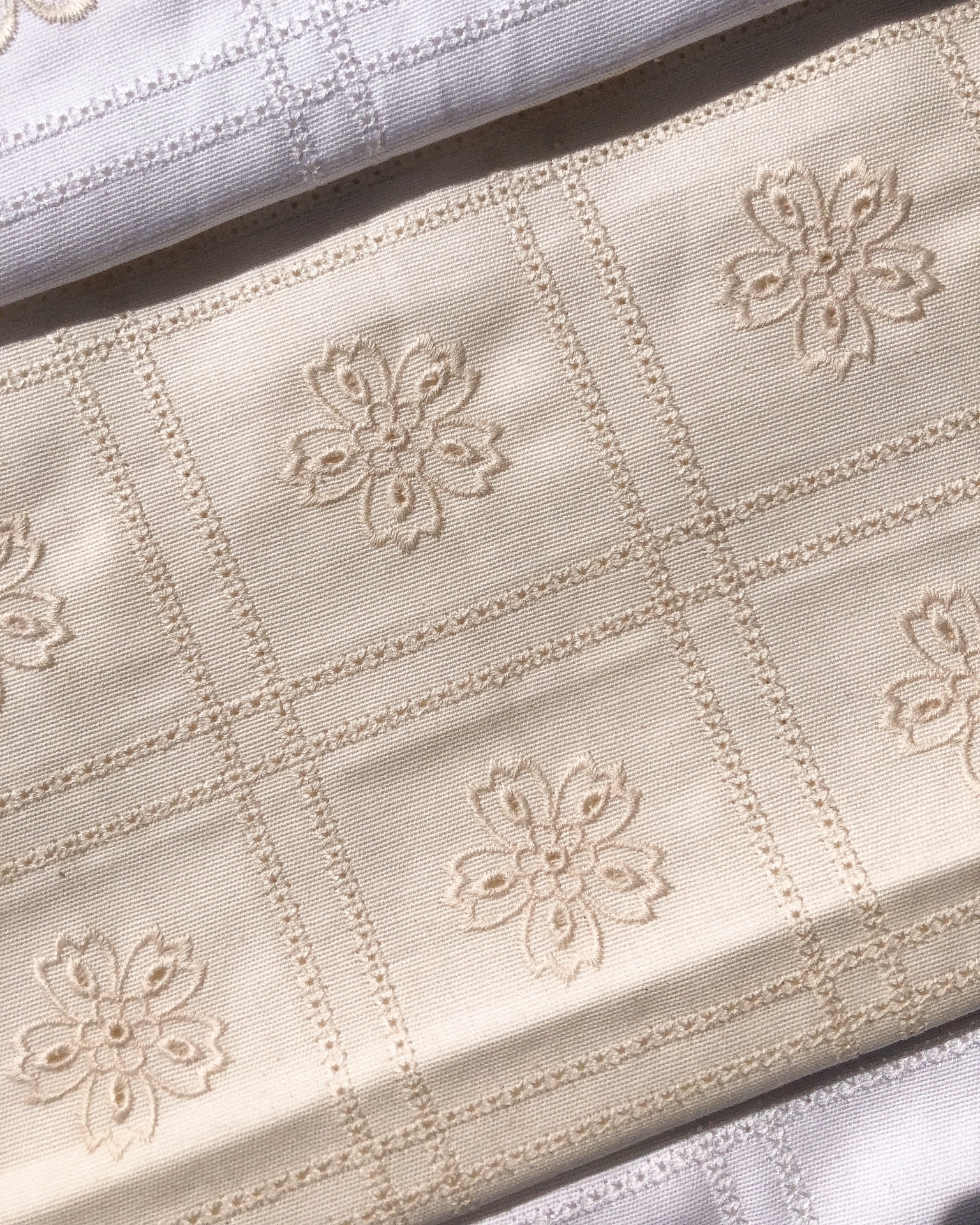 Tecido bege com flores bordadas e padrão em quadros