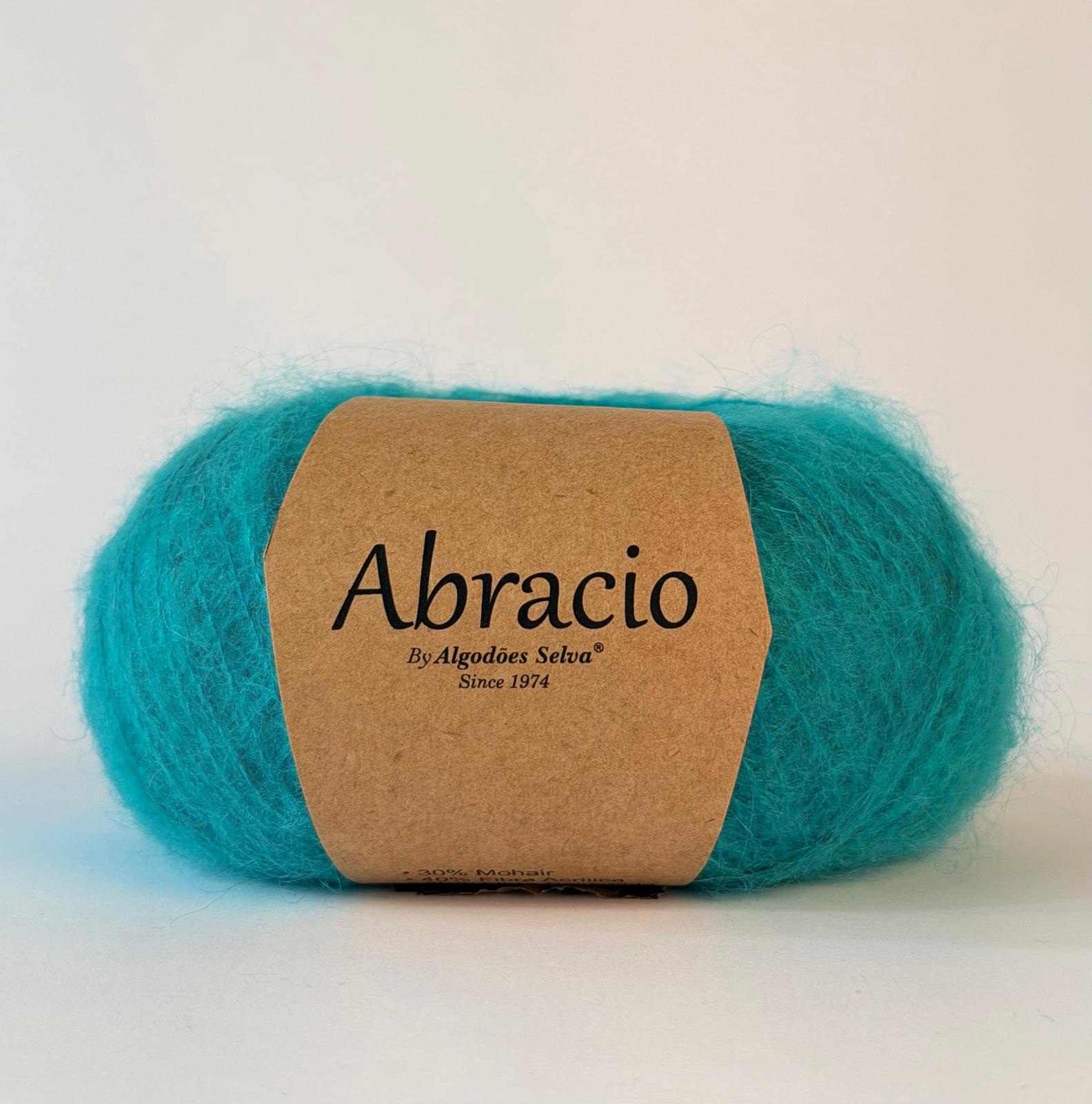 Novelo de lã azul turquesa com etiqueta castanha de papel Abracio