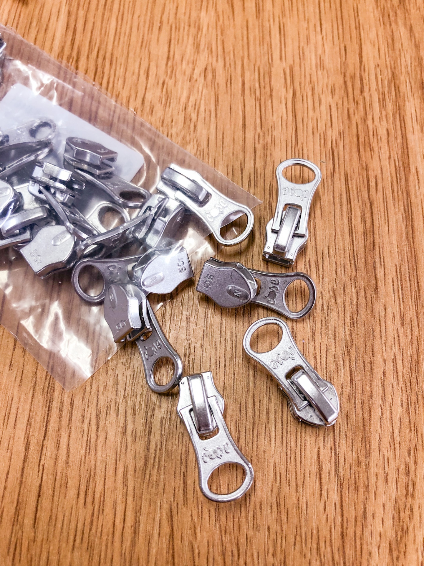 cursores metálicos de fecho éclair prateados numa mesa de madeira