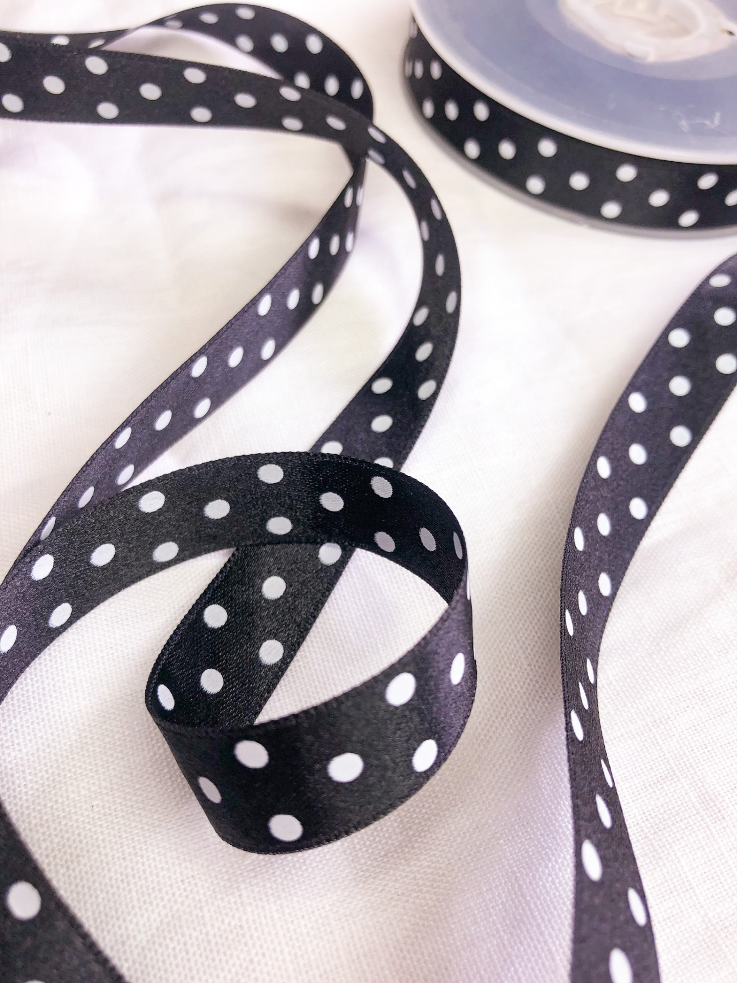 Fita preta com bolinhas brancas enrolada sobre fundo branco