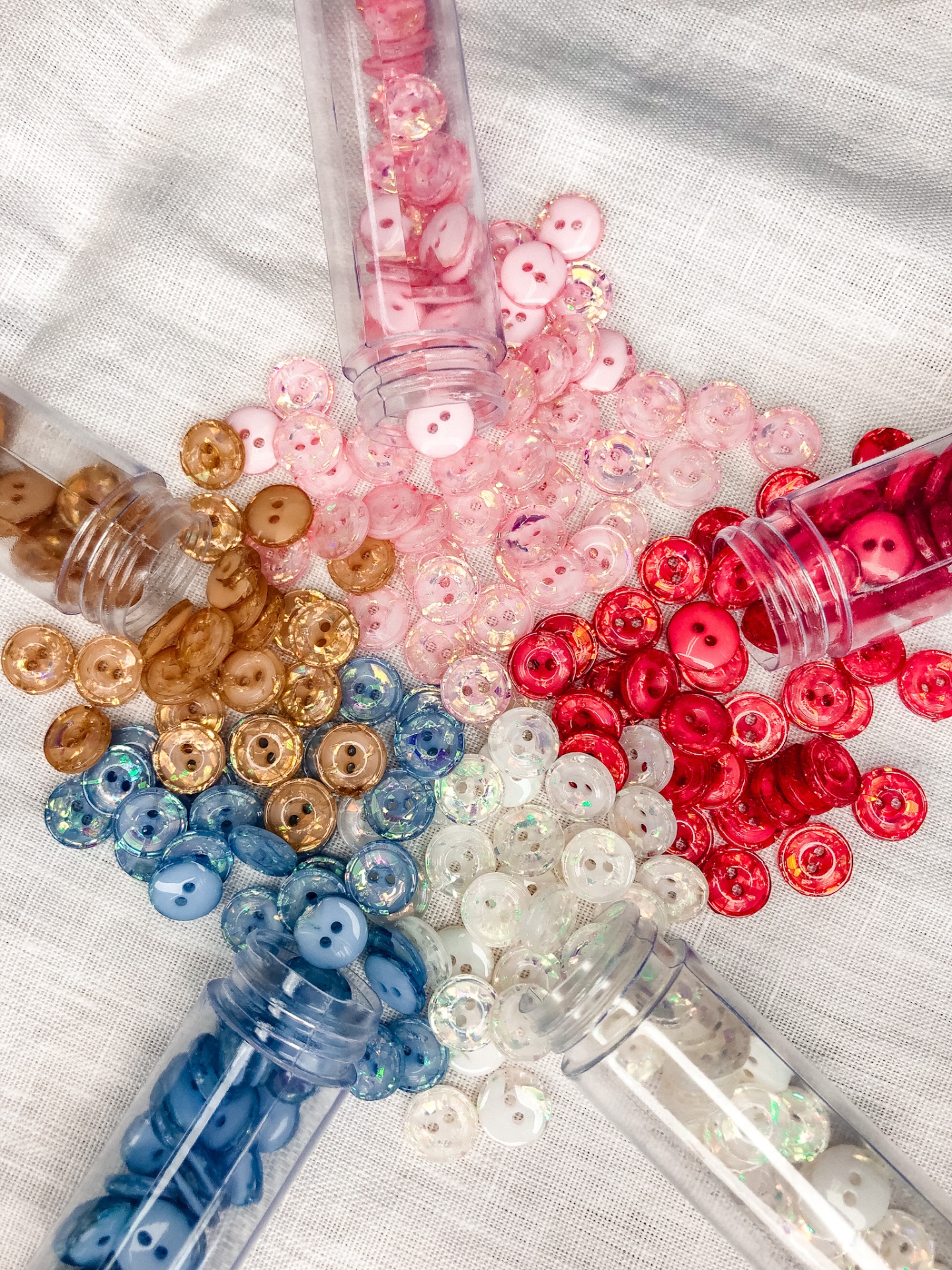 Botões coloridos pequenos espalhados com embalagens cilíndricas transparentes