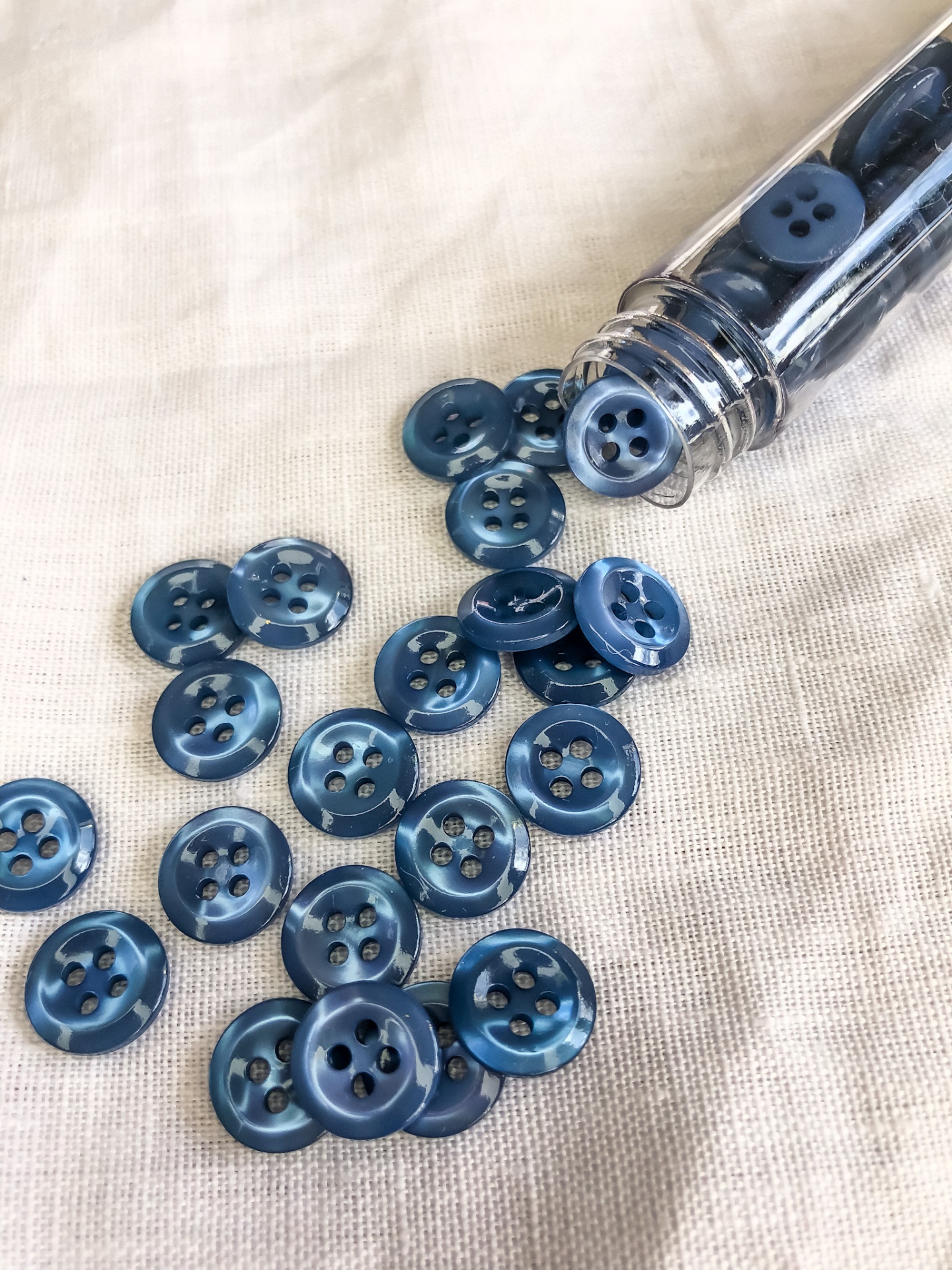 Botões azuis de plástico com quatro furos e frasco transparente