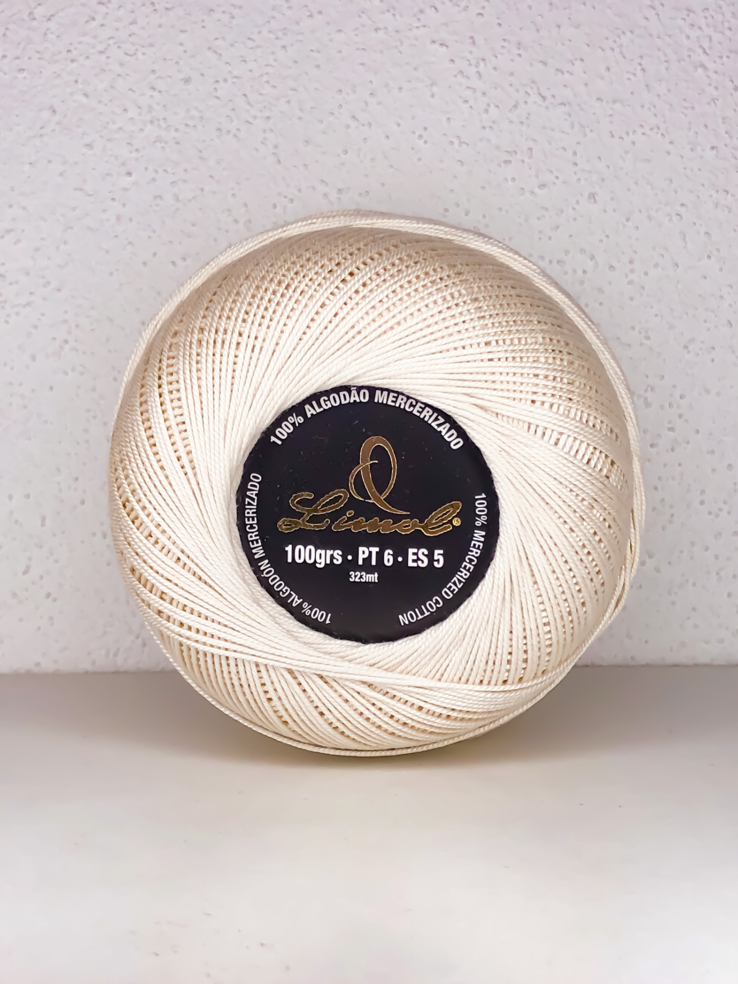 Rolo de linha de algodão mercerizado branco com etiqueta preta e texto central