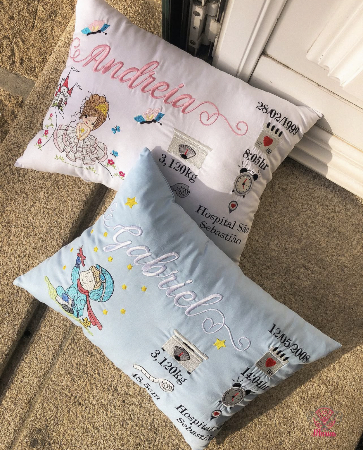 Duas almofadas personalizadas em branco e azul claro com nomes e detalhes bordados