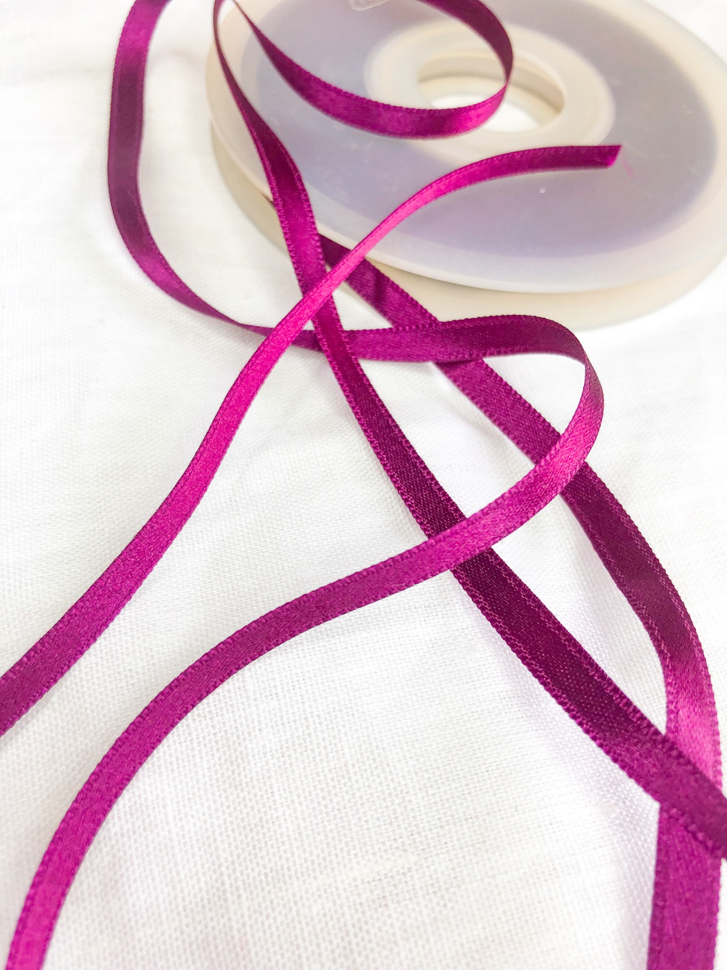 Fita de cetim fúcsia sobre carretel branco transparente