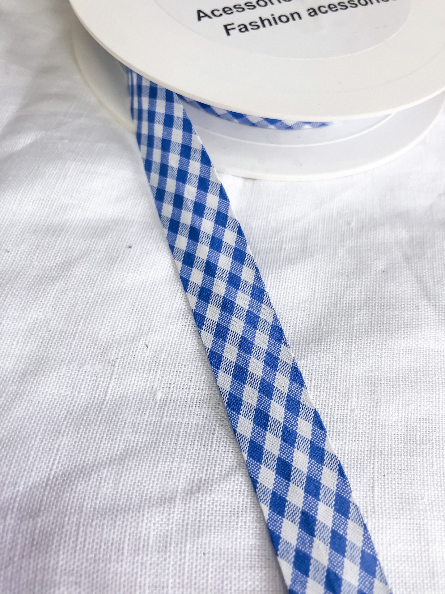 Fita xadrez azul e branco em carretel branco sobre tecido branco