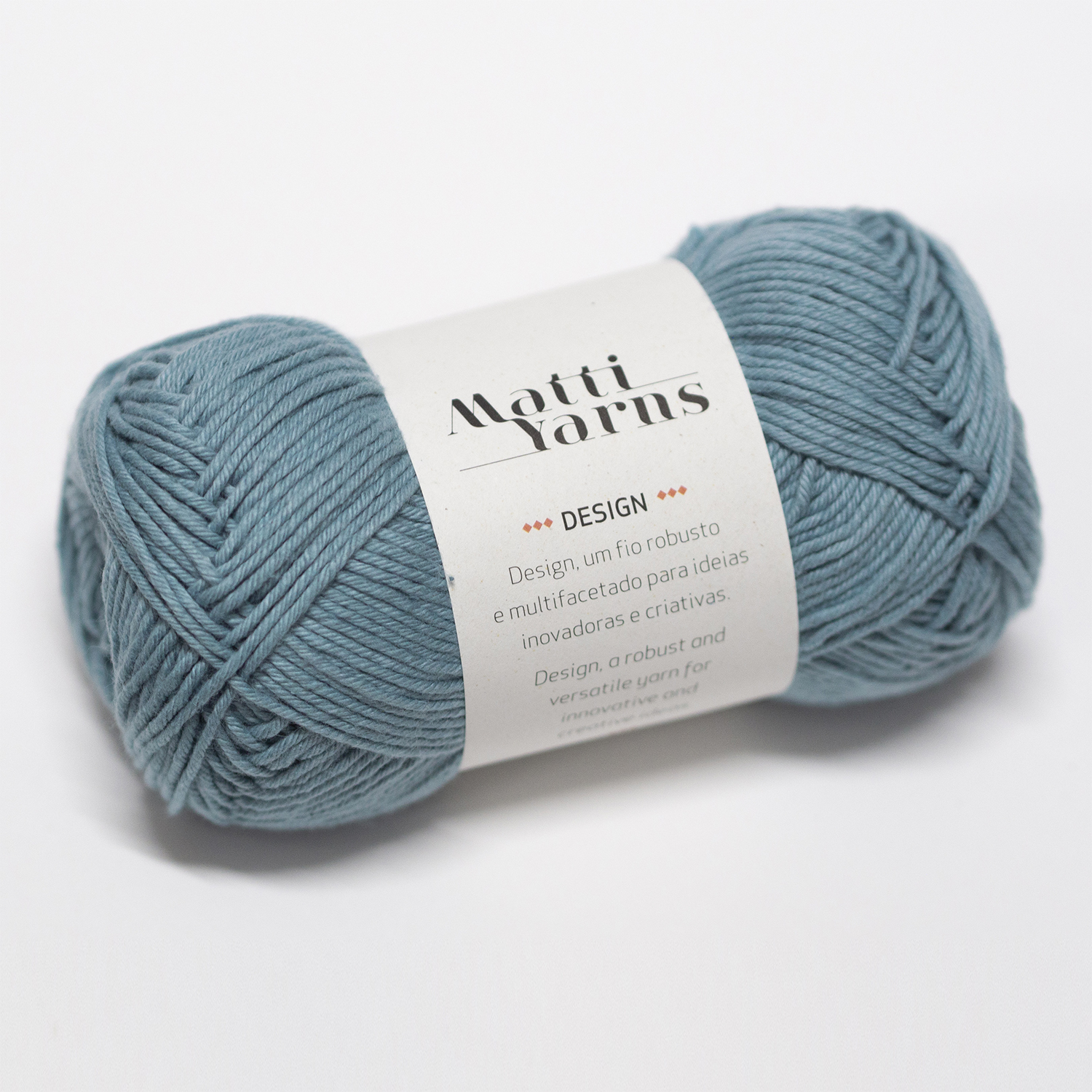 Novelo de lã azul acinzentada com etiqueta branca da marca Motti Yarns