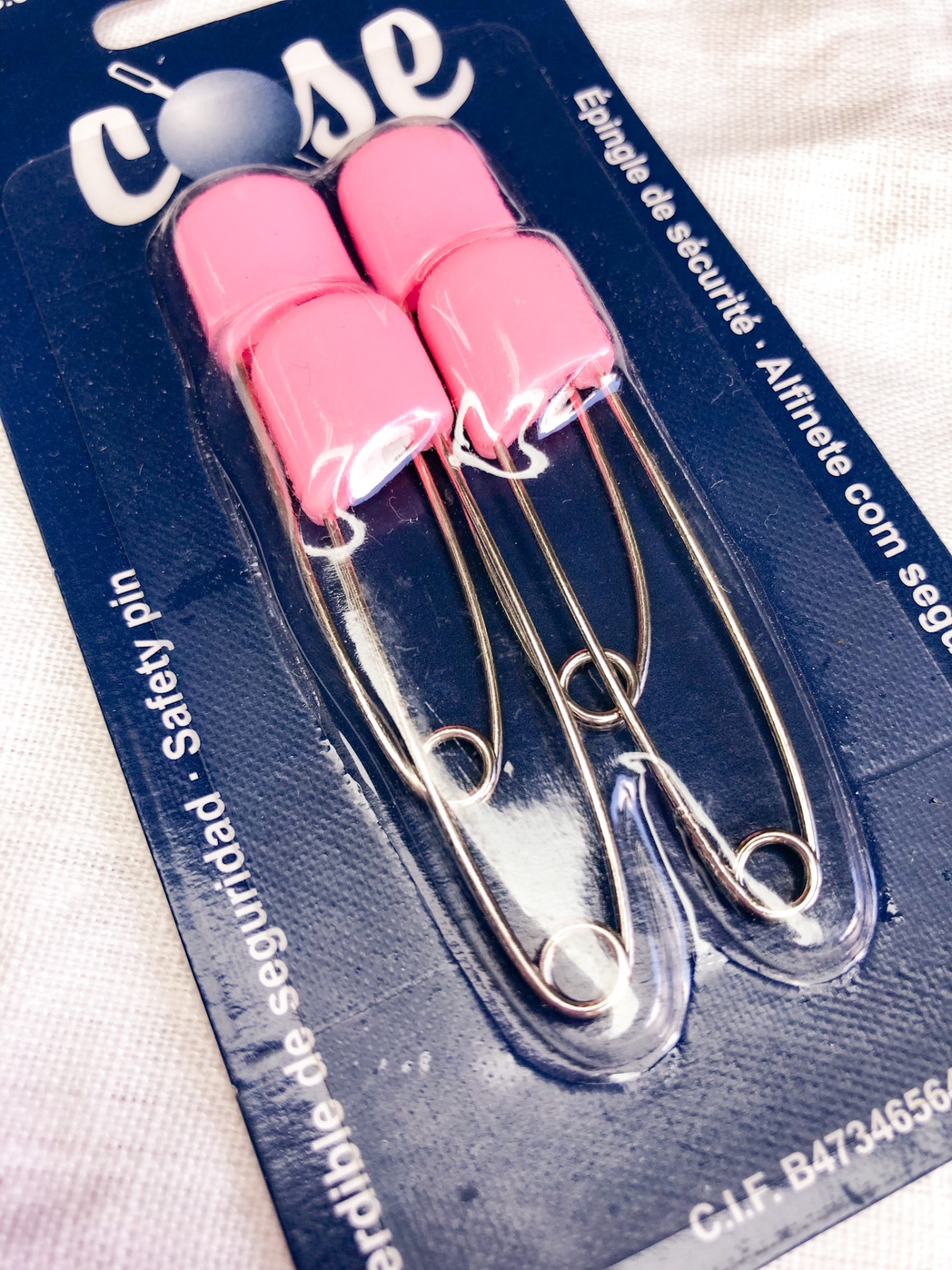 Conjunto de dois alfinetes de segurança rosa em embalagem azul
