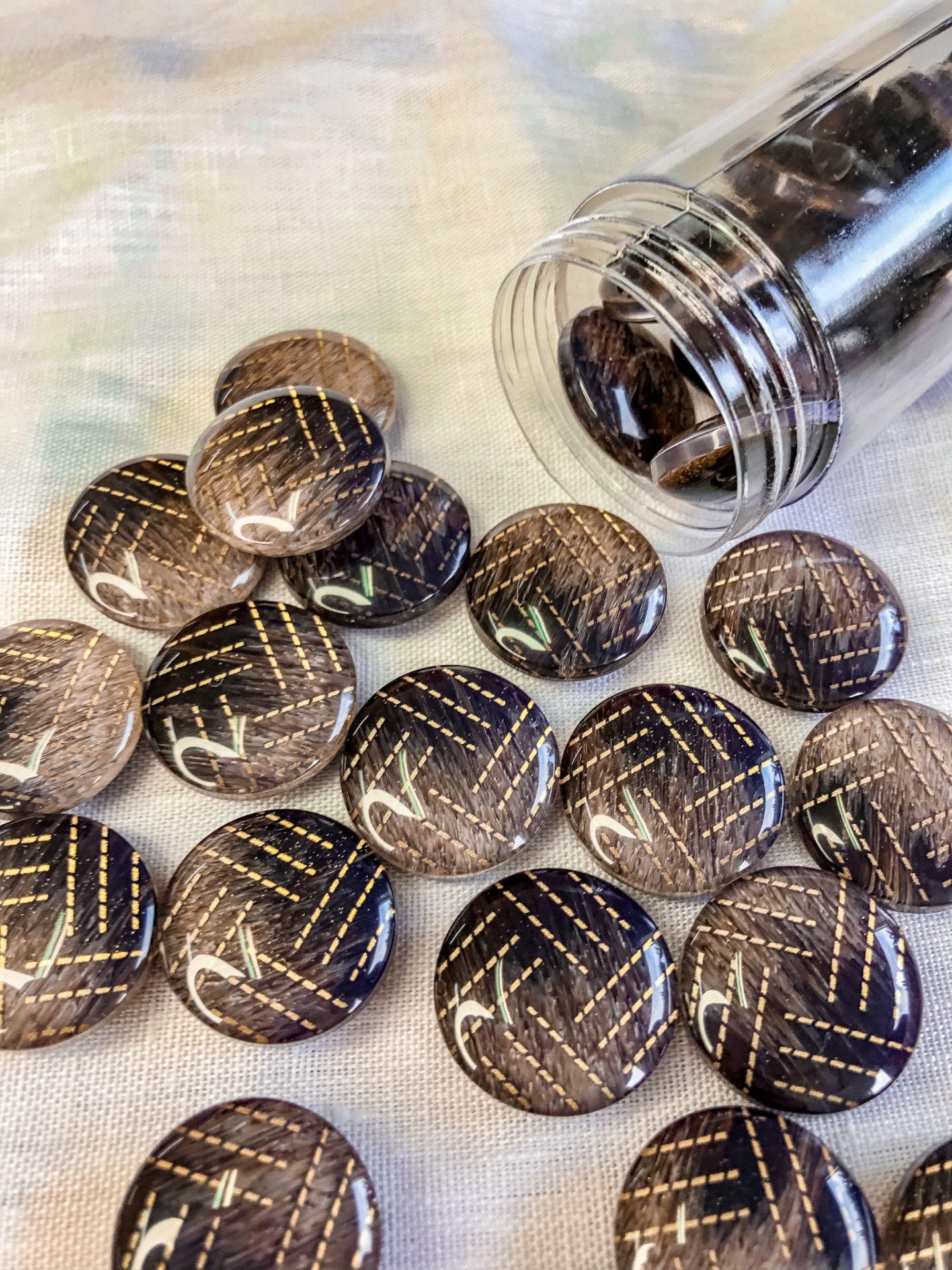 Botões redondos pretos com padrão listrado castanho e branco sobre tecido claro