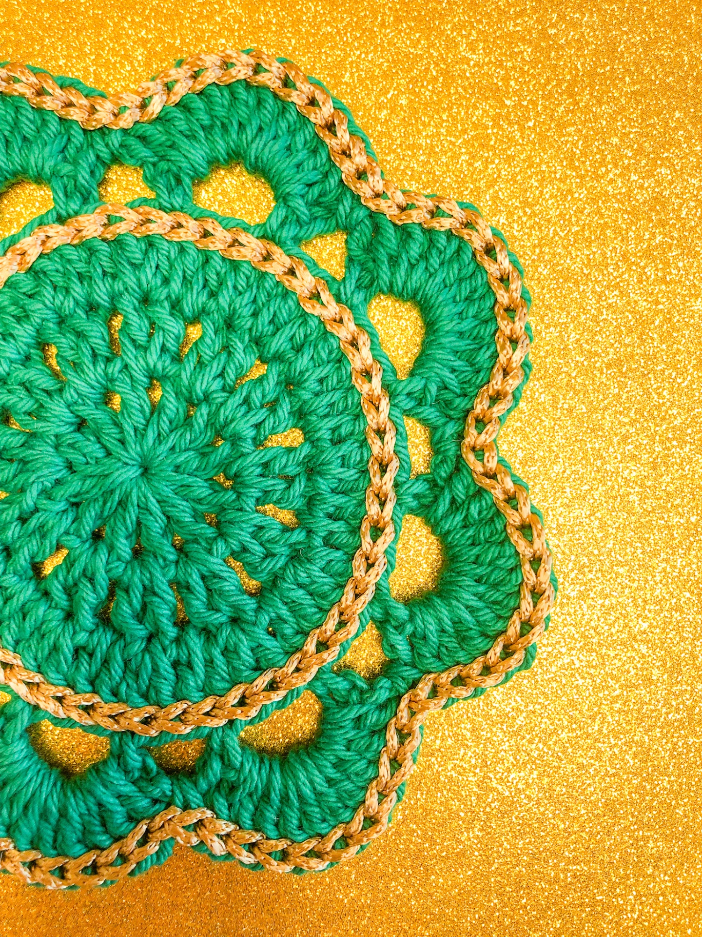 Peça de croché verde e amarela sobre superfície dourada