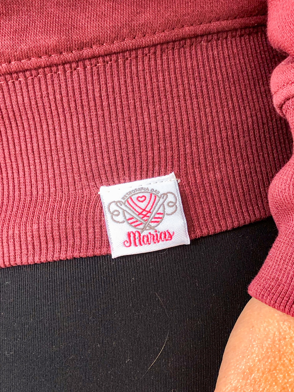 Etiqueta branca numa peça de roupa vermelha com canelado e fundo preto