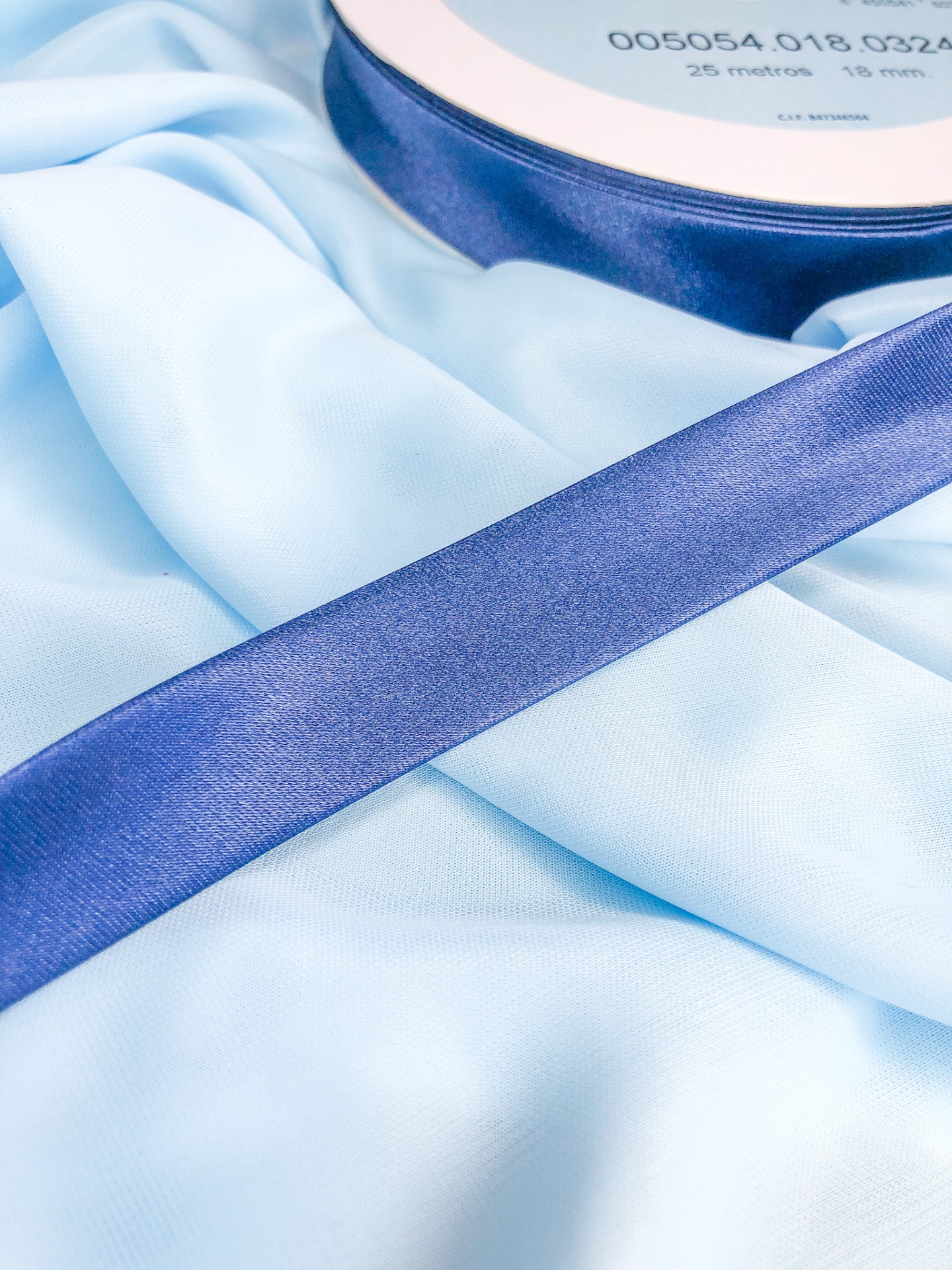 Rolo de fita de cetim azul escuro sobre tecido azul claro