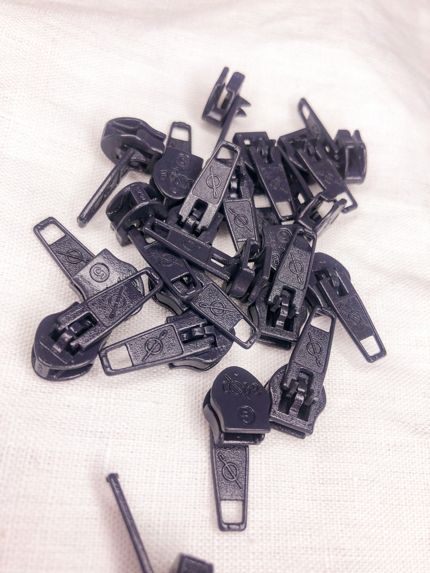 Puxadores de fecho éclair pretos em plástico sobre tecido branco