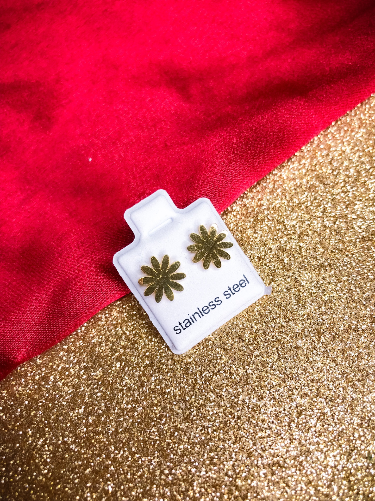 Brincos dourados em aço inoxidável em forma de flores na embalagem branca