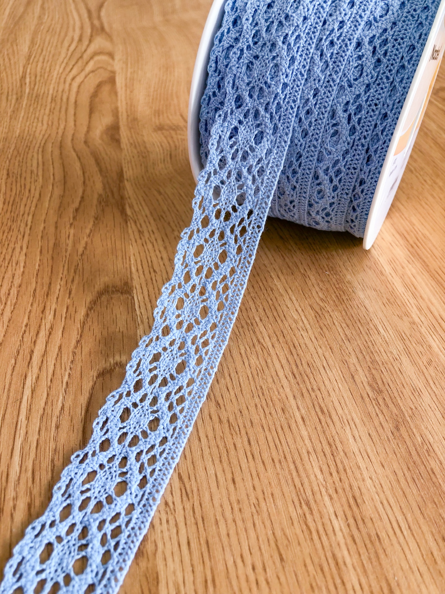 Rolo de renda azul rendada sobre madeira clara