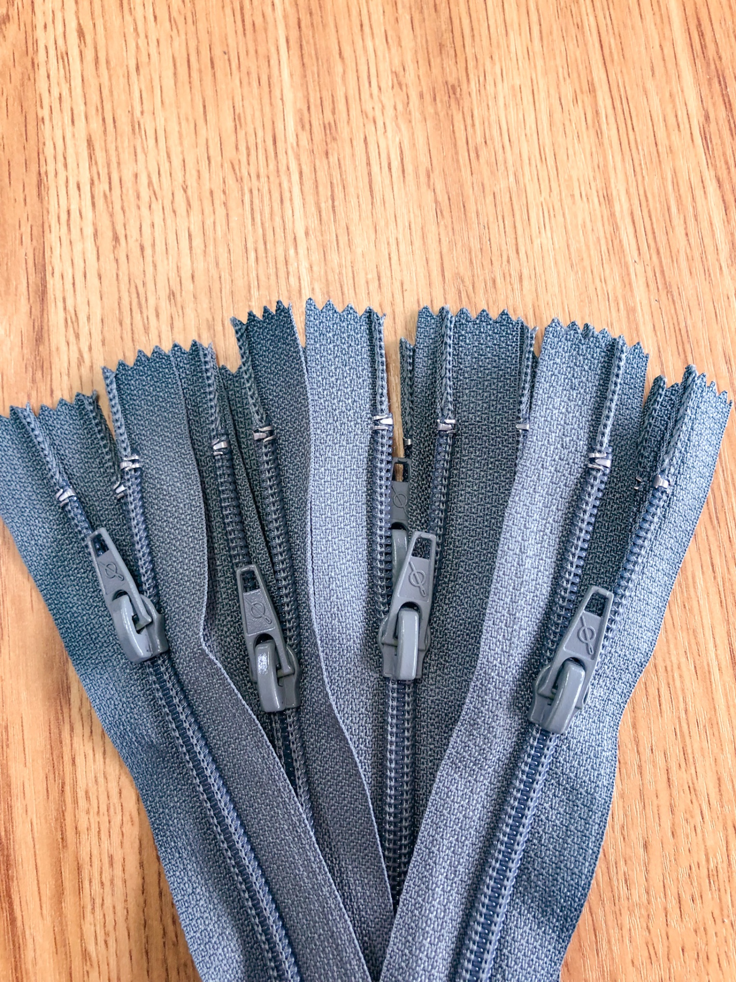 Cinco fechos éclair cinzentos sobre madeira