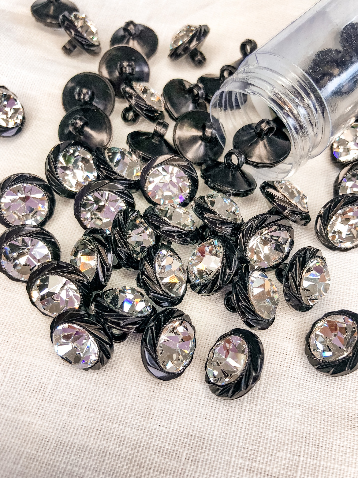 Botões decorativos com pedra brilhante e base preta, espalhados em tecido