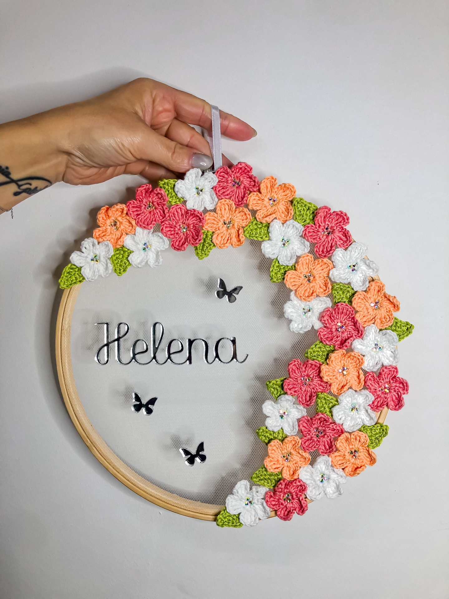 Guirlanda com flores de crochê coloridas e nome Helena em tule com base de madeira