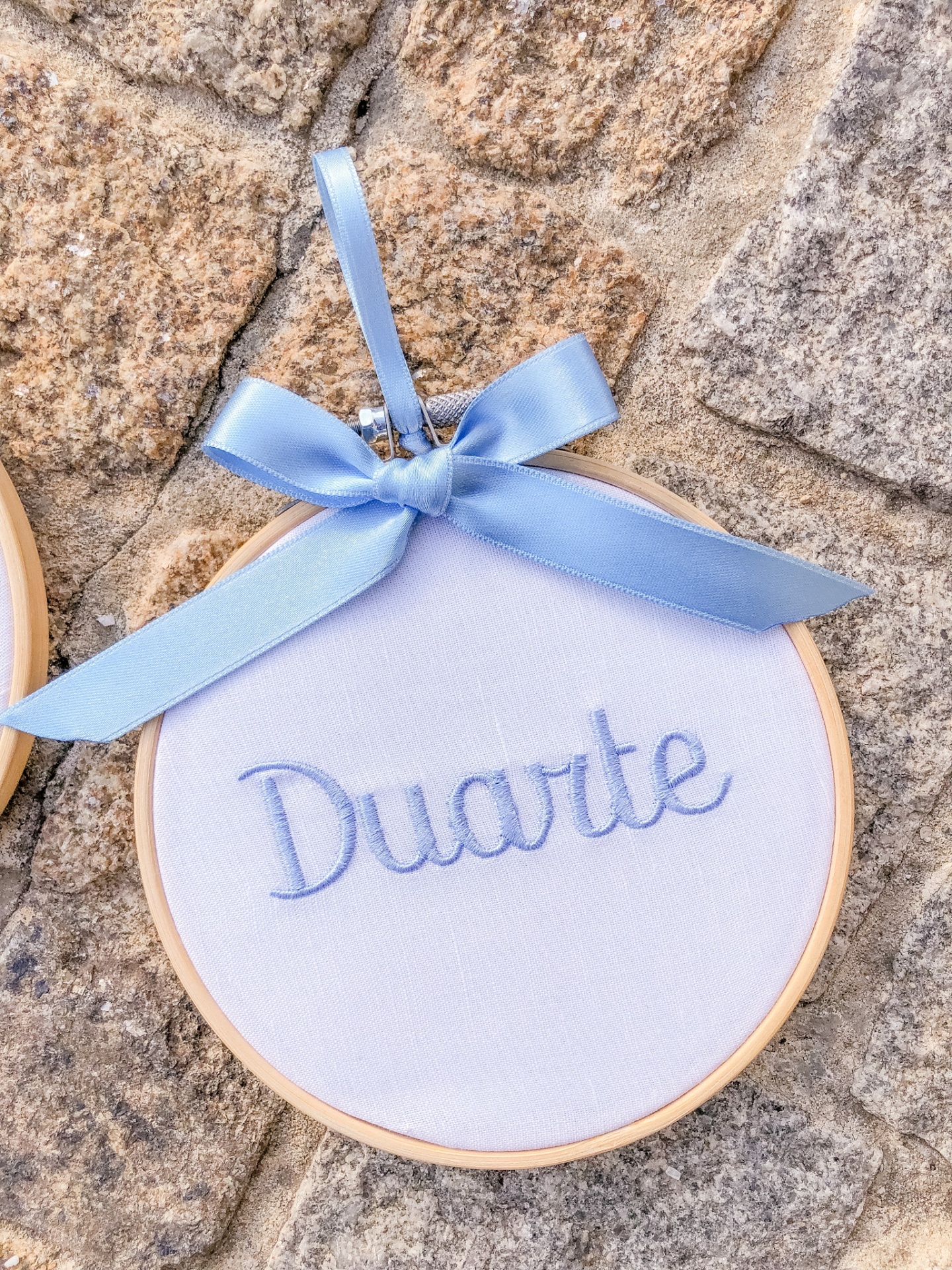 Aro de bordado redondo com nome Duarte bordado e laço azul sobre pedra
