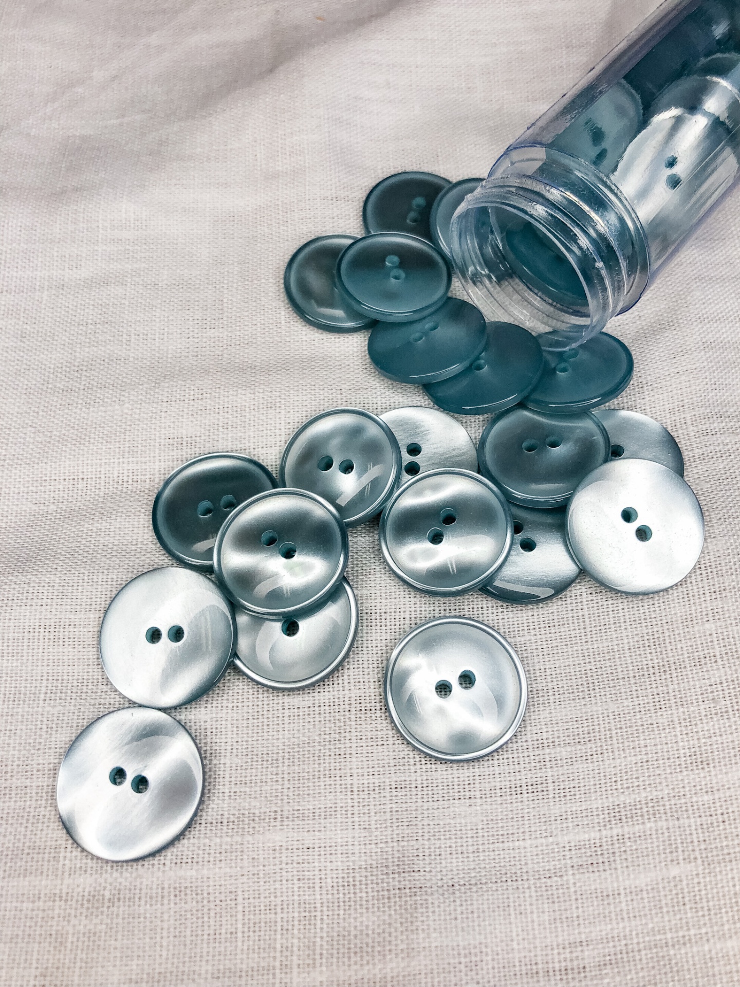 botões redondos cinza sobre tecido bege com frasco plástico