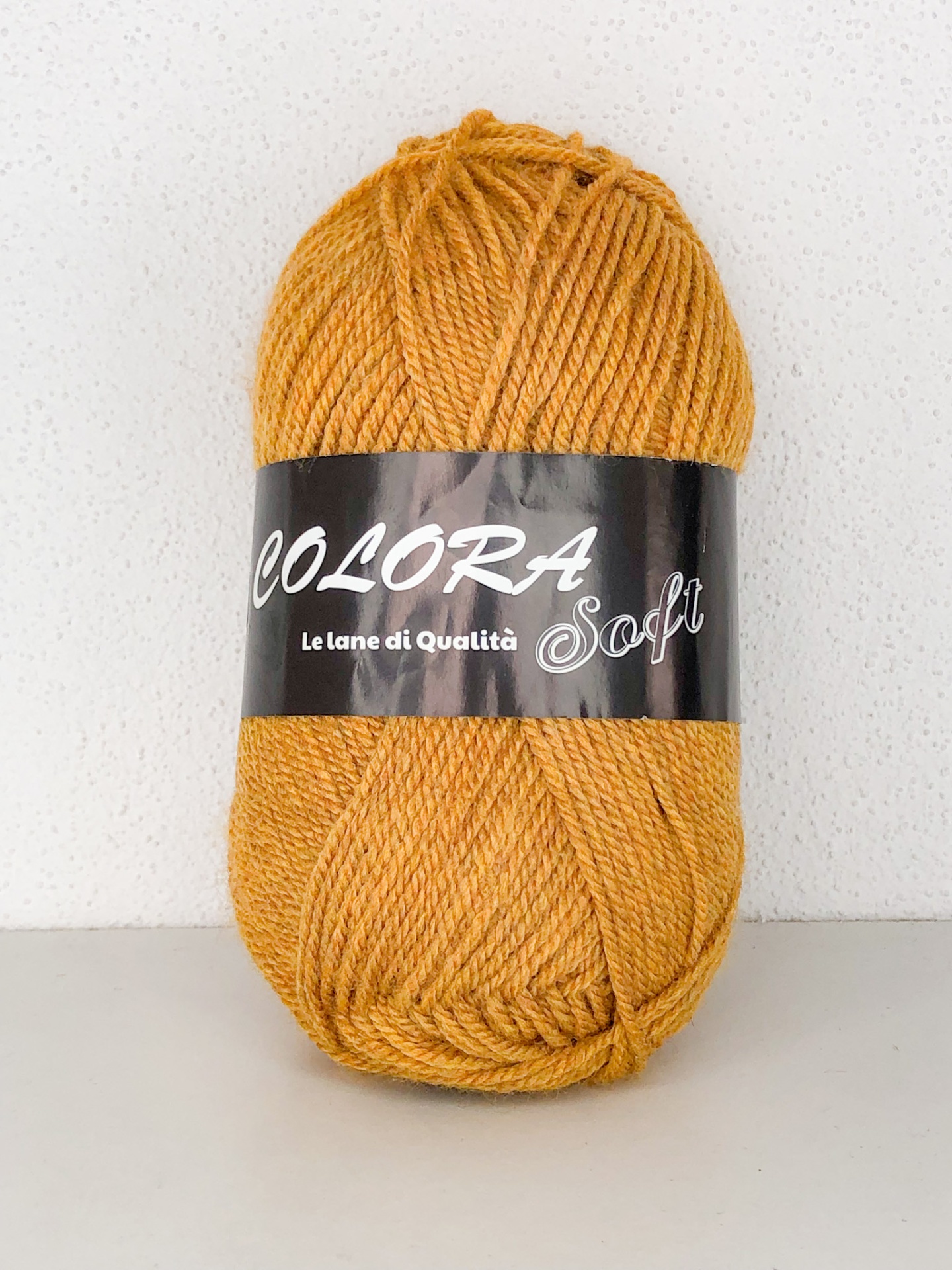 Novelo de lã amarelo-mostarda com etiqueta preta e branca