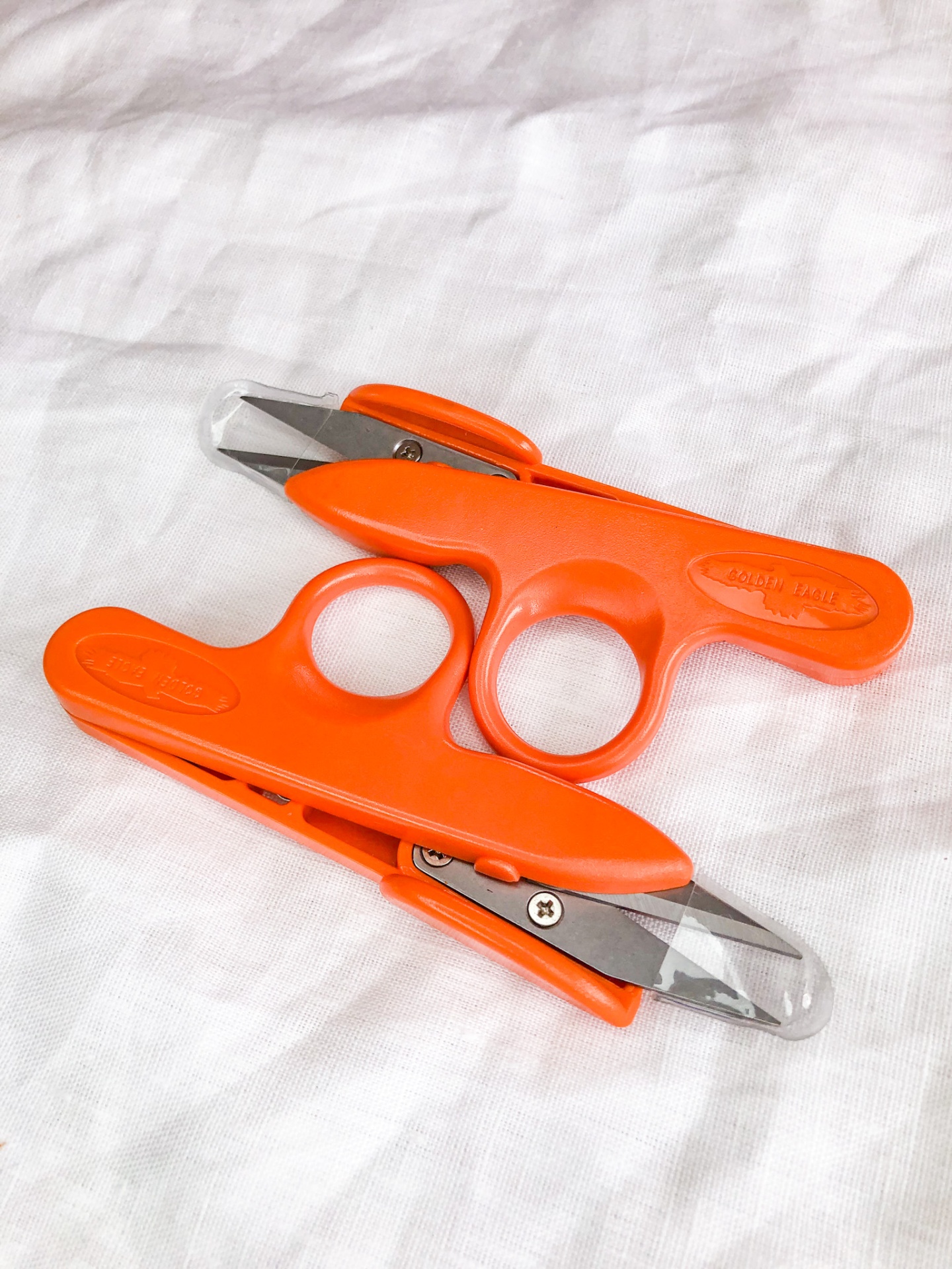 Dois corta unhas laranja sobre tecido branco