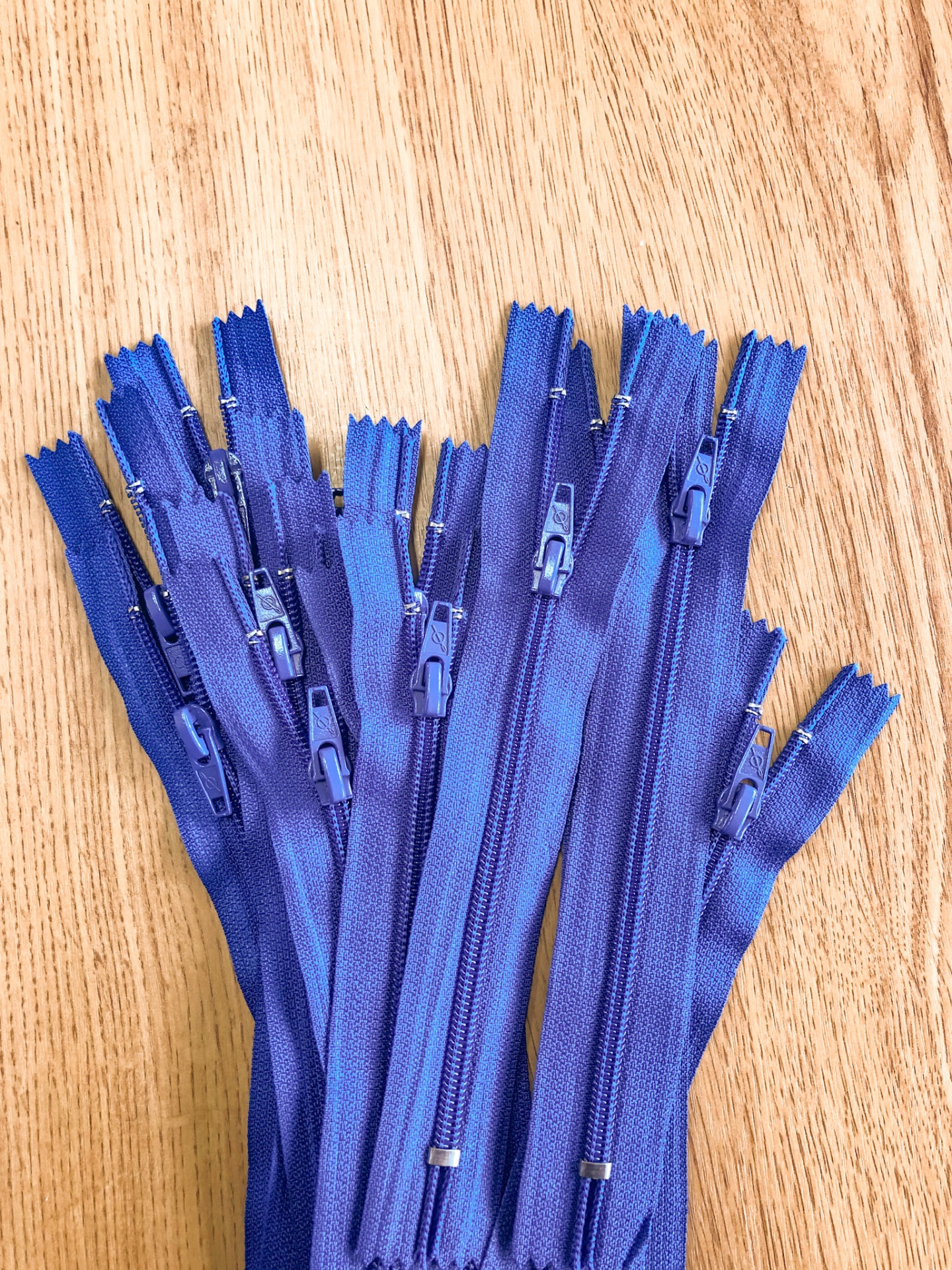 Vários fechos de correr azuis com cursores azuis sobre fundo de madeira clara